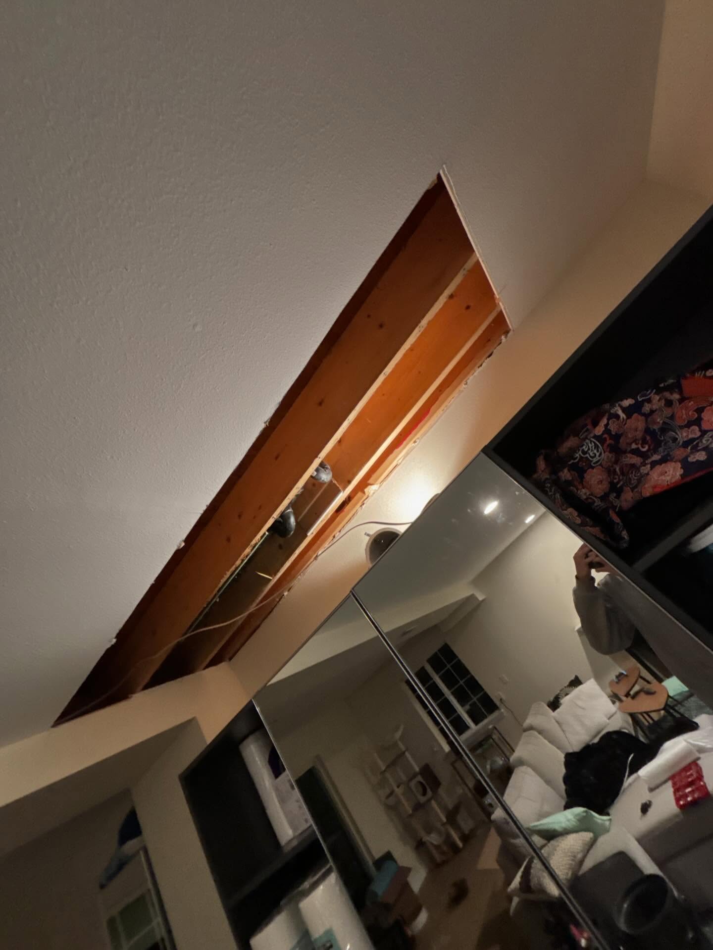 Ceiling opened in a clean strip exposing joists and wiring