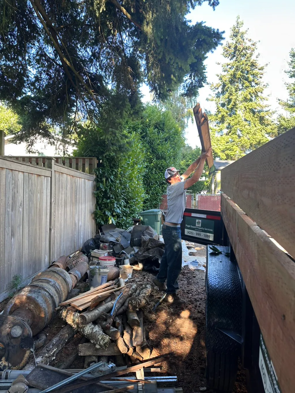 PSPS crew member hand-loading old fence boards into a dump trailer