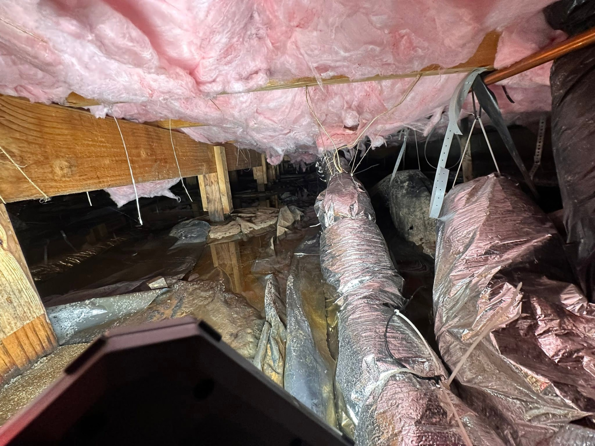 Crawlspace with wet insulation and flex duct on the ground