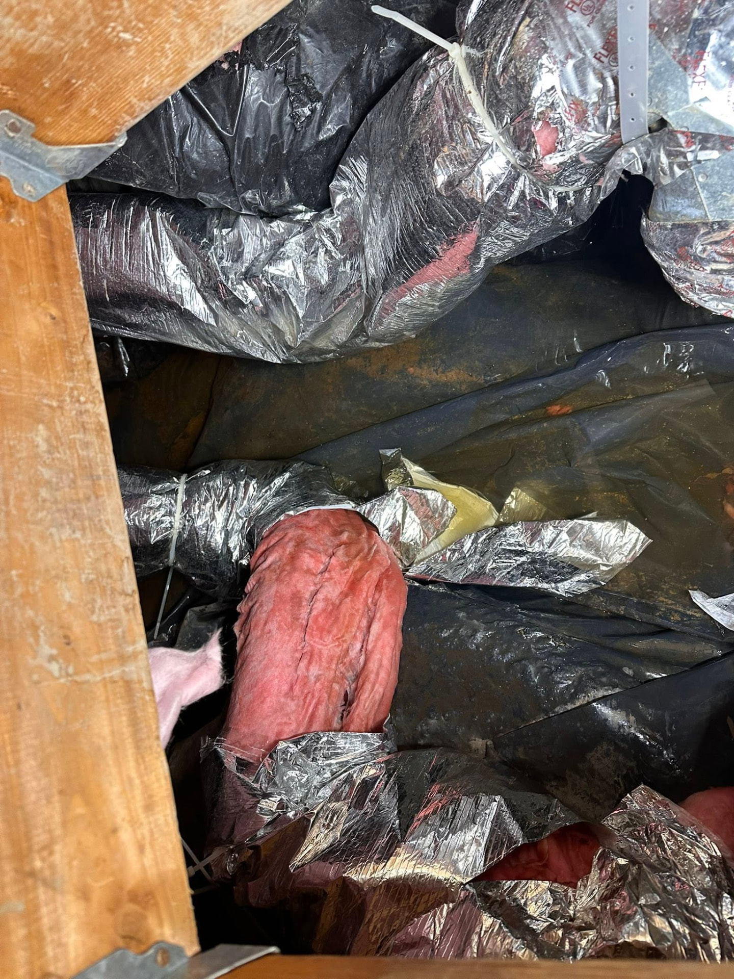Saturated insulation and torn duct wrap pulled out of a crawlspace