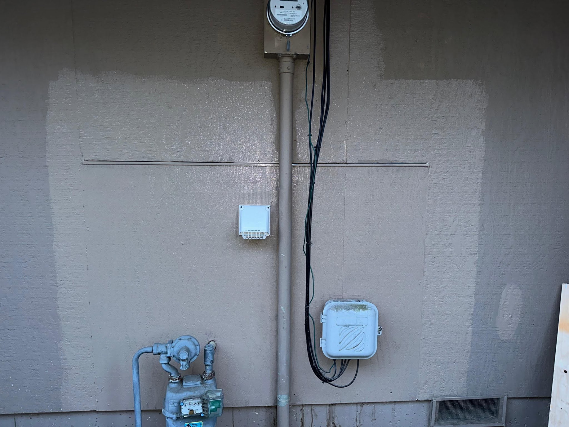 Repaired and patched exterior stucco wall with sealed penetrations and meters