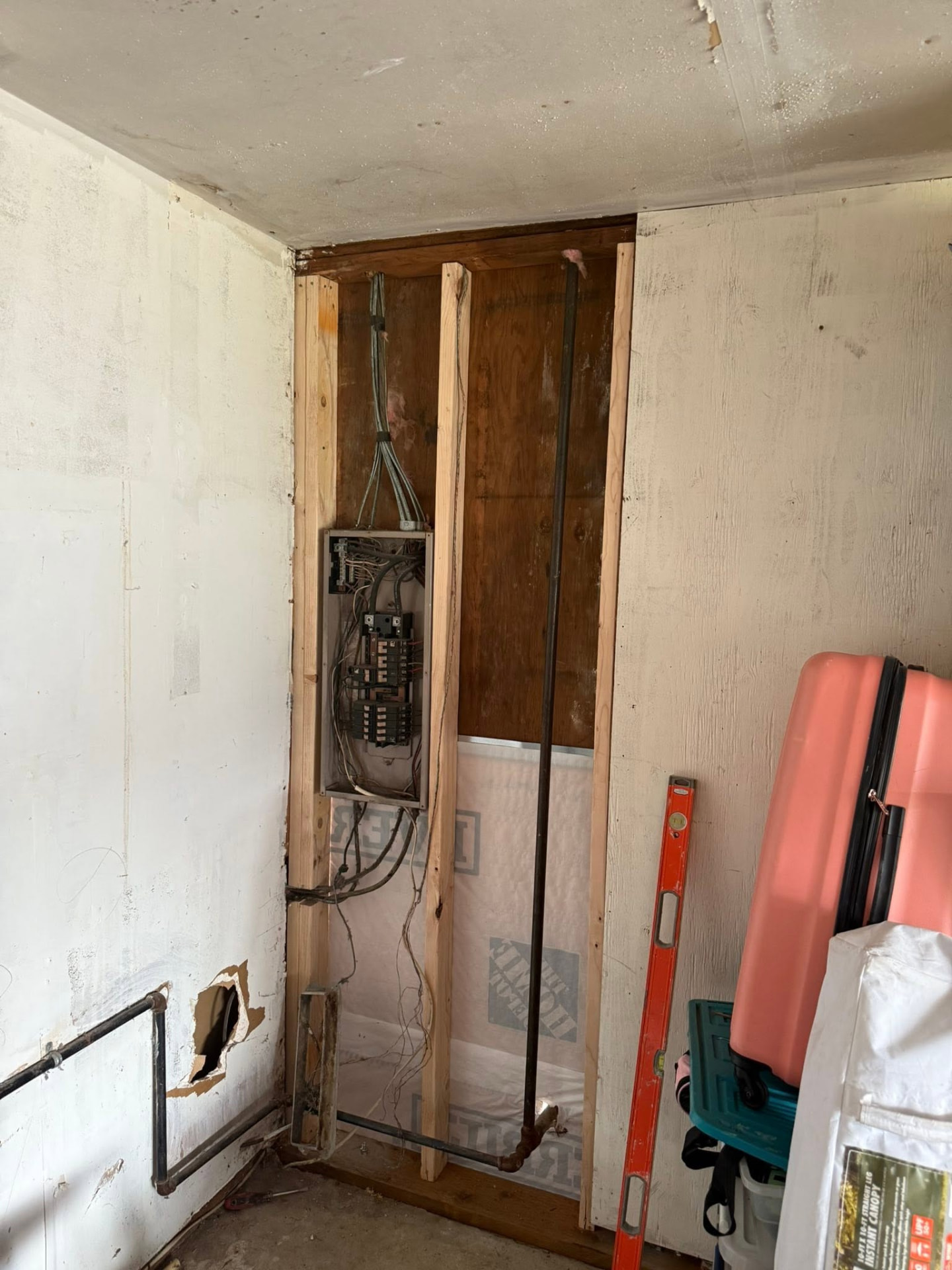 Interior wall opened around an electrical panel with new studs and weather barrier