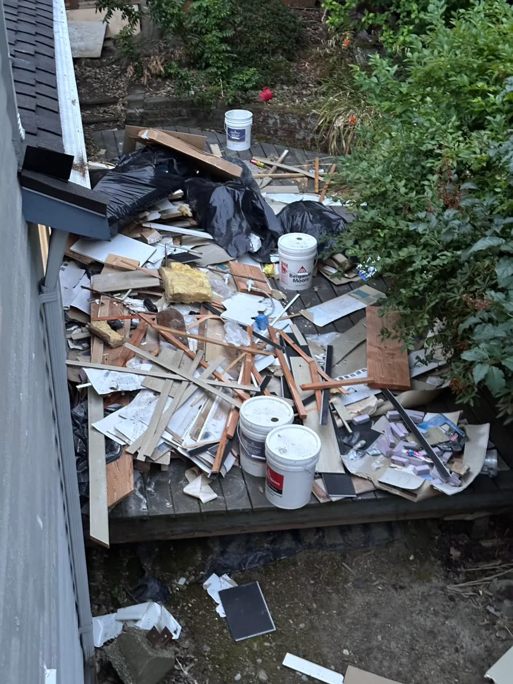 Deck covered in tile offcuts, paint buckets and construction debris after a remodel